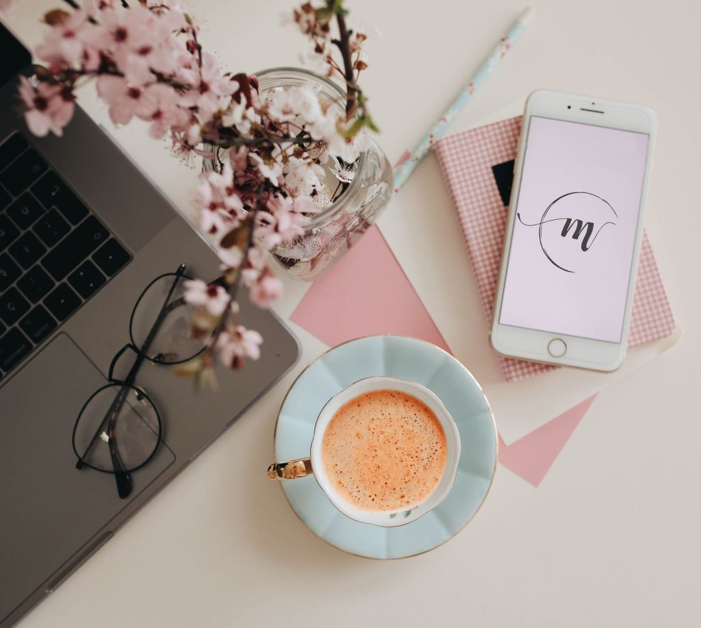 Chic workspace featuring a laptop, coffee, and cherry blossoms, perfect for creative inspiration.